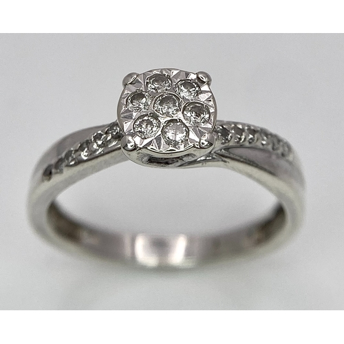 425 - A 9K White Gold Diamond Cluster Ring. Seven small diamonds on a circular base with diamonds on wings... 