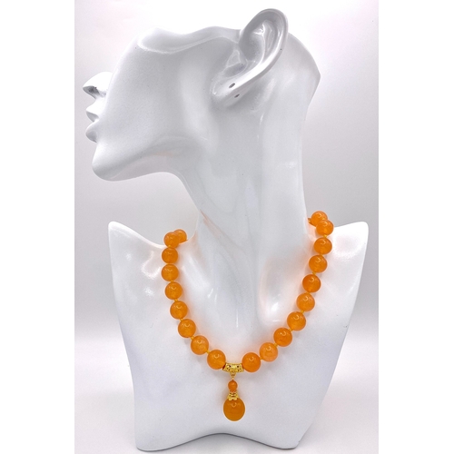 519 - A Summery Orange Jade Beaded Necklace with Drop Pendant. 12mm beads. Gilded accents and clasp. 3.5cm... 