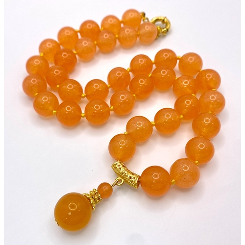 519 - A Summery Orange Jade Beaded Necklace with Drop Pendant. 12mm beads. Gilded accents and clasp. 3.5cm... 