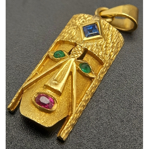 219 - A 18K (STAMPED AND TESTED AS) YELLOW GOLD CONGOLESE MASK PENDANT SET WITH SAPPHIRE, EMERALDS AND RUB... 