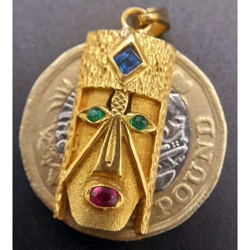 219 - A 18K (STAMPED AND TESTED AS) YELLOW GOLD CONGOLESE MASK PENDANT SET WITH SAPPHIRE, EMERALDS AND RUB... 