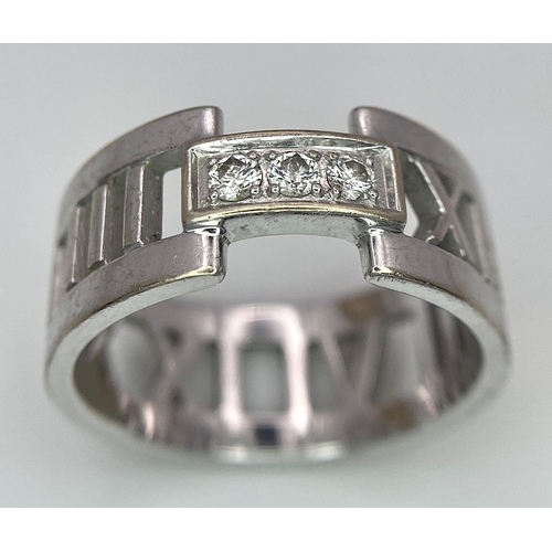 611 - An 18K White Gold Tiffany Atlas Diamond Ring. Pierced Roman numeral decoration. Tiffany mark. Size N... 