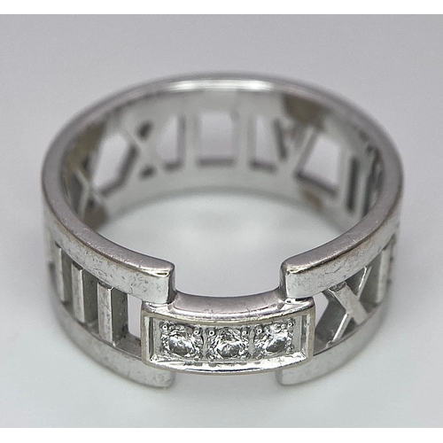 611 - An 18K White Gold Tiffany Atlas Diamond Ring. Pierced Roman numeral decoration. Tiffany mark. Size N... 