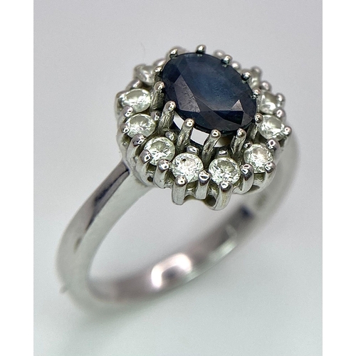 618 - A 14K White Gold Sapphire and Diamond Ring. Oval cut central sapphire with a 0.5ctw diamond surround... 