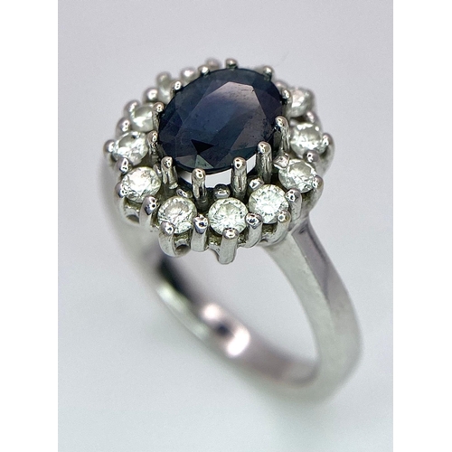 618 - A 14K White Gold Sapphire and Diamond Ring. Oval cut central sapphire with a 0.5ctw diamond surround... 