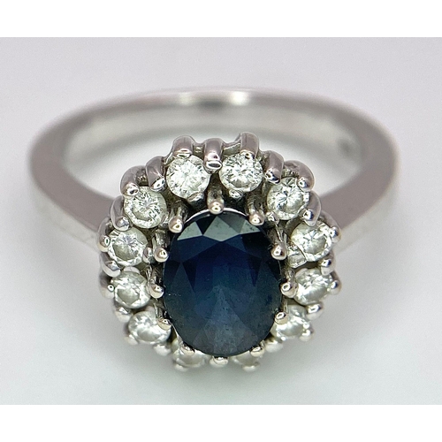 618 - A 14K White Gold Sapphire and Diamond Ring. Oval cut central sapphire with a 0.5ctw diamond surround... 