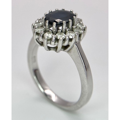 618 - A 14K White Gold Sapphire and Diamond Ring. Oval cut central sapphire with a 0.5ctw diamond surround... 