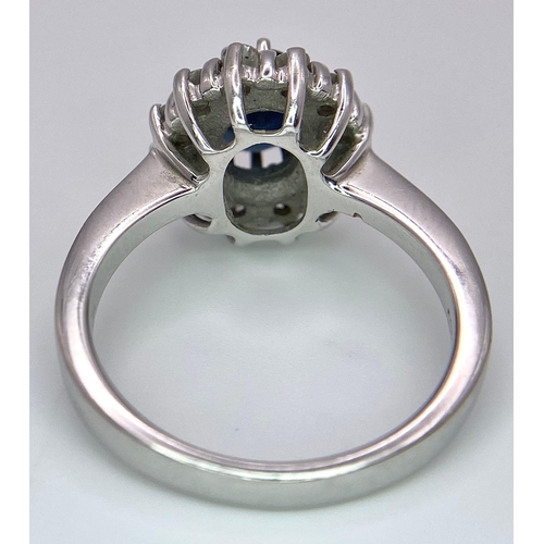 618 - A 14K White Gold Sapphire and Diamond Ring. Oval cut central sapphire with a 0.5ctw diamond surround... 