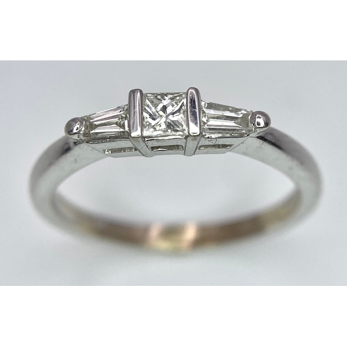 165 - AN 18K WHITE GOLD, DIAMOND 3 STONE RING - PRINCESS CUT CENTRE WITH A TAPPERED BAGUETTE DIAMOND EITHE... 