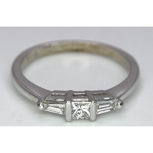 165 - AN 18K WHITE GOLD, DIAMOND 3 STONE RING - PRINCESS CUT CENTRE WITH A TAPPERED BAGUETTE DIAMOND EITHE... 