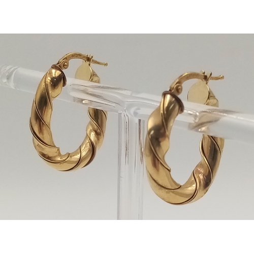 408 - A 9 K yellow gold pair of hoop earrings with a twisted design, drop: 26 mm, total weight: 5 g.