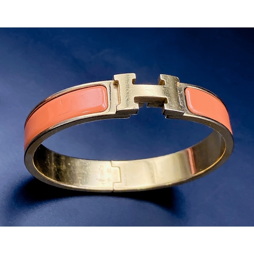 254 - A Hermes Gold Plated and Inlaid Orange Enamel Bangle. 6cm inner diameter. Comes with original Hermes... 