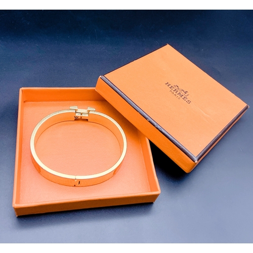 254 - A Hermes Gold Plated and Inlaid Orange Enamel Bangle. 6cm inner diameter. Comes with original Hermes... 