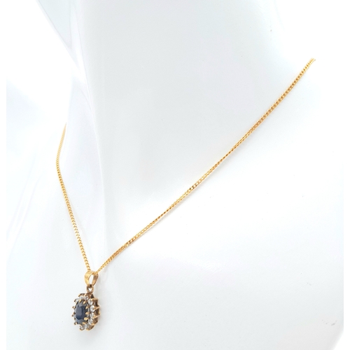 325 - A 9 K yellow gold chain necklace carrying a pendant  with an oval cut dark blue sapphire surrounded ... 