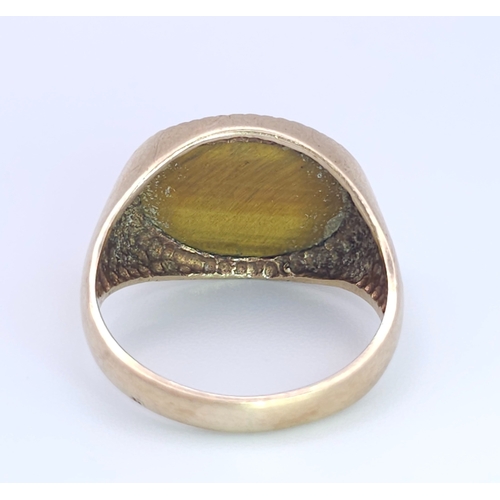 457 - A 9 K yellow gold cygnet ring with a quality tiger's eye oval flat cabochon, size: Q, weight: 4.3 g