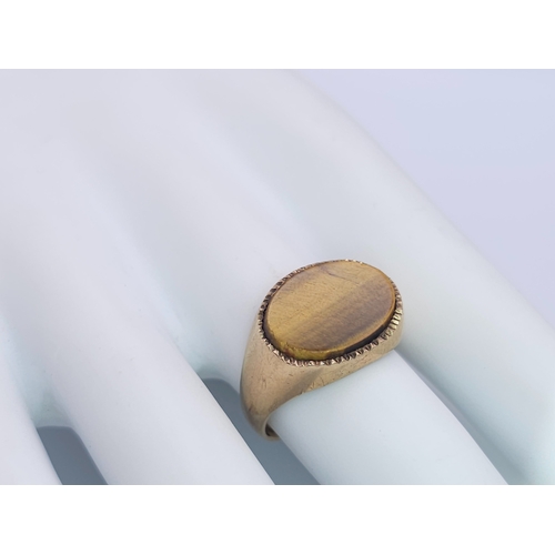 457 - A 9 K yellow gold cygnet ring with a quality tiger's eye oval flat cabochon, size: Q, weight: 4.3 g