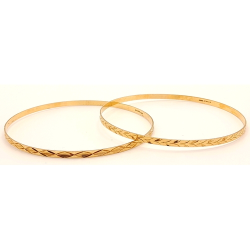 473 - A pair of  9 K yellow gold bangles, each with a  different  design but perfectly complementing each ... 