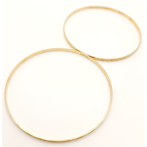 473 - A pair of  9 K yellow gold bangles, each with a  different  design but perfectly complementing each ... 