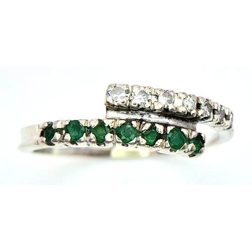 481 - A 14K WHITE GOLD DIAMOND & EMERALD 2 ROW CROSSOVER RING. Size L, 1.6g total weight. Ref: SC 8077