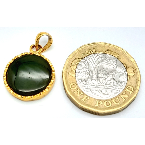 527 - A 9 K yellow gold pendant with a round green jade cabochon.  Diameter: 15 mm, weight: 2.4 g.