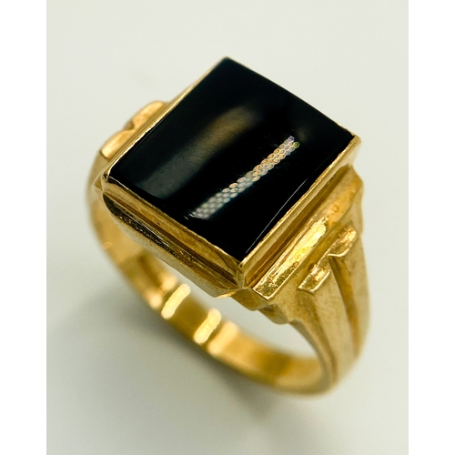 416 - A 9 K yellow gold cygnet ring with a black rectangular onyx cabochon and grooved shoulders. Size: U,... 