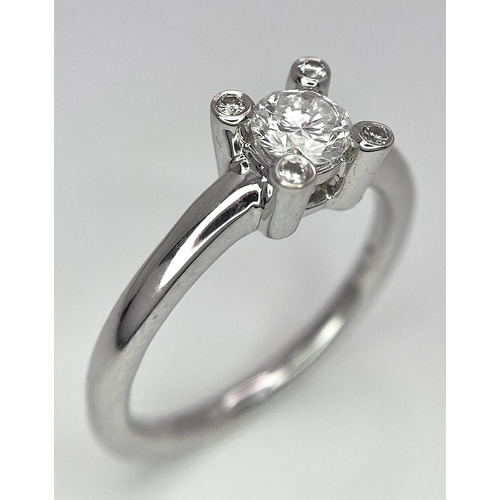 19 - AN 18K WHITE GOLD DIAMOND SOLITAIRE RING WITH FOUR DIAMOND TURRETS - 0.50CT 4.6G. SIZE M 1/2.