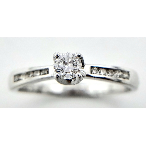 250 - AN 18K WHITE GOLD DIAMOND SOLITAIRE RING - WITH DIAMOND SHOULDERS. 0.25CT. 1.9G. SIZE L