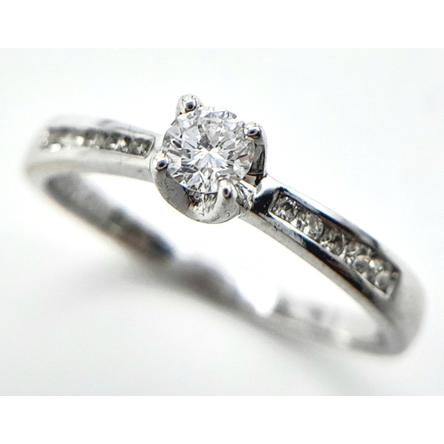 250 - AN 18K WHITE GOLD DIAMOND SOLITAIRE RING - WITH DIAMOND SHOULDERS. 0.25CT. 1.9G. SIZE L