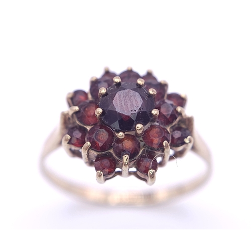 723 - A vintage 9 K yellow gold ring with a cluster of round cut garnets, size: Q, weight: 2.5 g.