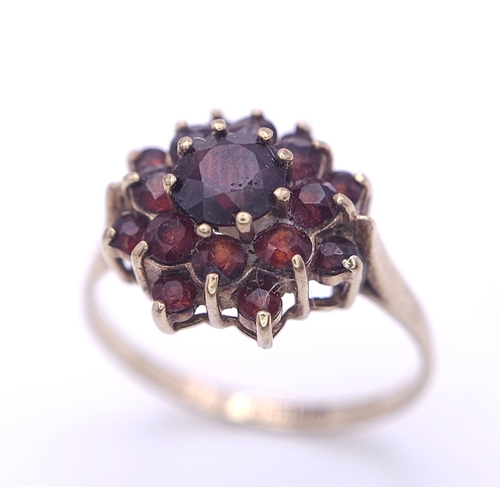 723 - A vintage 9 K yellow gold ring with a cluster of round cut garnets, size: Q, weight: 2.5 g.