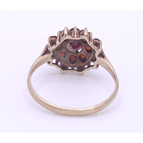 723 - A vintage 9 K yellow gold ring with a cluster of round cut garnets, size: Q, weight: 2.5 g.