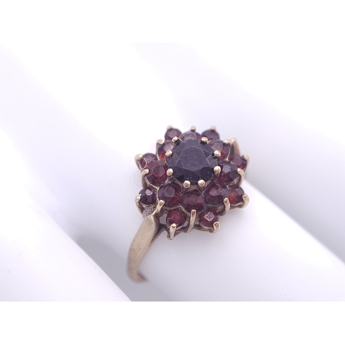 723 - A vintage 9 K yellow gold ring with a cluster of round cut garnets, size: Q, weight: 2.5 g.