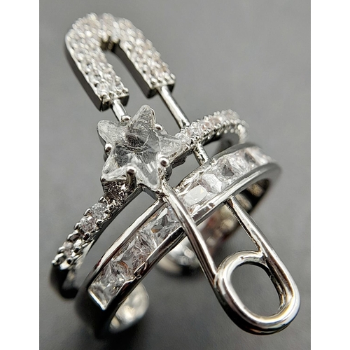 265 - A very fashionable, designer style, white metal (untested) ring with a safety pin and numerous cubic... 