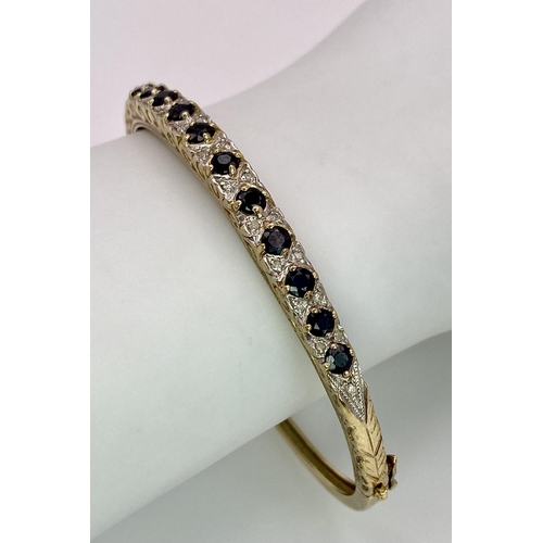 40 - A 9K YELLOW GOLD DIAMOND & SAPPHIRE SET BANGLE 10.4G , 55mm x 63mm diameter.

SC 9005