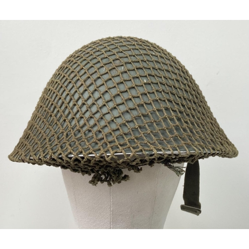 498 - A British Army Mark V steel helmet, complete with camouflage net. Very good condition