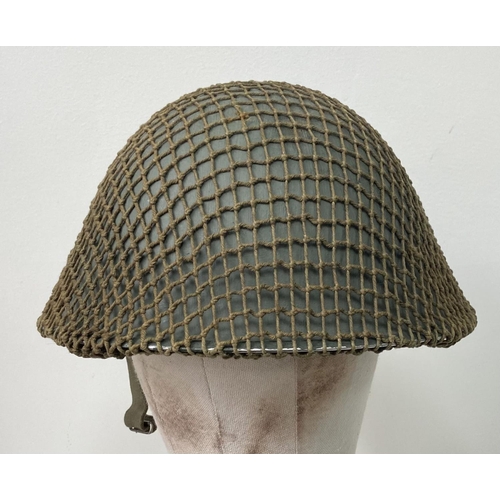 498 - A British Army Mark V steel helmet, complete with camouflage net. Very good condition