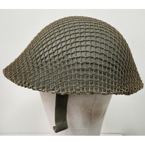 498 - A British Army Mark V steel helmet, complete with camouflage net. Very good condition