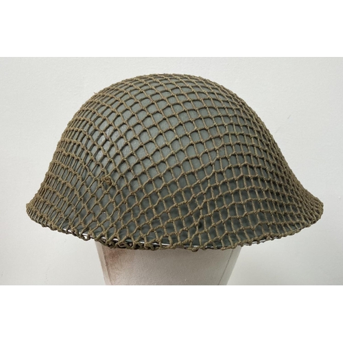 498 - A British Army Mark V steel helmet, complete with camouflage net. Very good condition