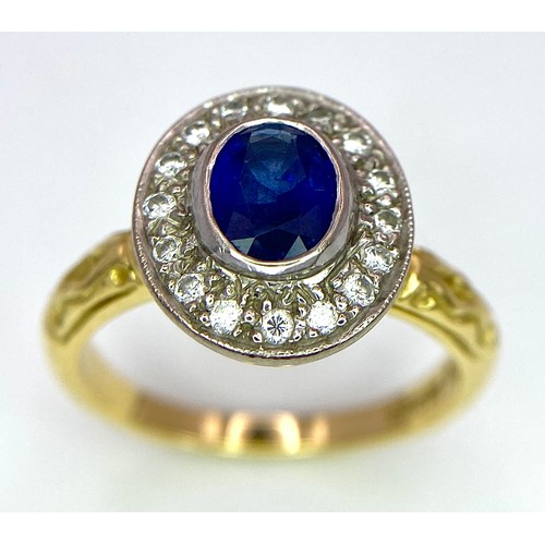 267 - An 18 K yellow gold ring with an oval cut blue sapphire surrounded by a halo of round cut diamonds a... 