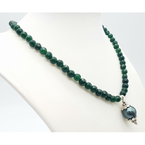 992 - A Small Emerald Beaded Necklace with Hanging Shell Pendant. 36cm necklace. 2.5cm pendant.