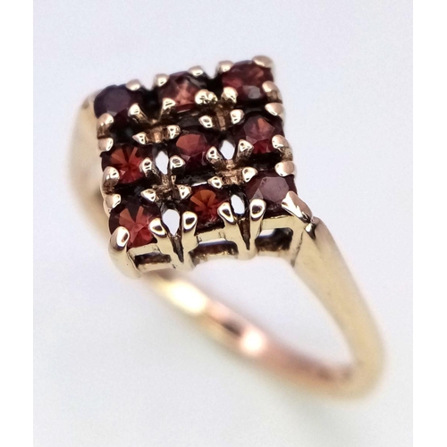 418 - A 9K YELLOW GOLD GARNET SET RING. 2.1G. SIZE K.