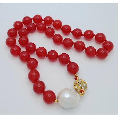 797 - A Fiery Red Jade Bead Necklace with a Baroque Pearl Interrupter. 12mm beads. 44cm necklace length. G... 