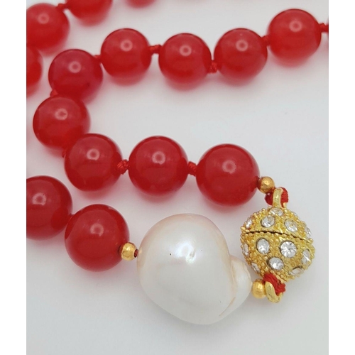 797 - A Fiery Red Jade Bead Necklace with a Baroque Pearl Interrupter. 12mm beads. 44cm necklace length. G... 