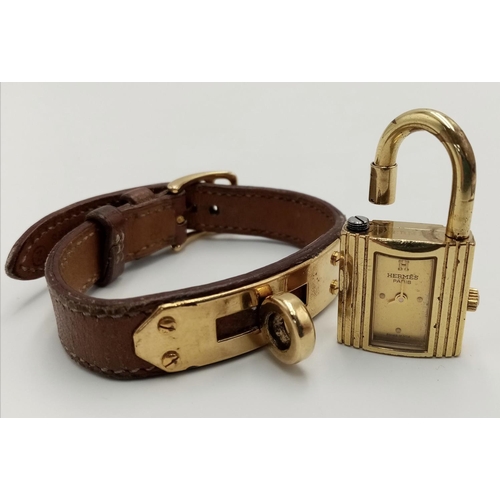 745 - A Hermes Kelly Watch. Brown leather strap. Gold plated padlock quartz watch. Needs a battery so as f... 