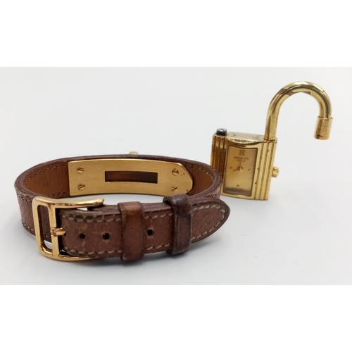 745 - A Hermes Kelly Watch. Brown leather strap. Gold plated padlock quartz watch. Needs a battery so as f... 