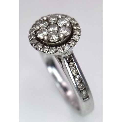 747 - A 9K White Gold Diamond Cluster Ring. Decorative floral shape. Size N. 4g total weight.