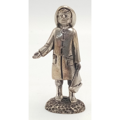 788 - A STERLING SILVER (TESTED AS) FIGURE OF A YOUNG BOY IN RAIN JACKET AND HAT WITH A BOAT POSSIBLY THE ... 