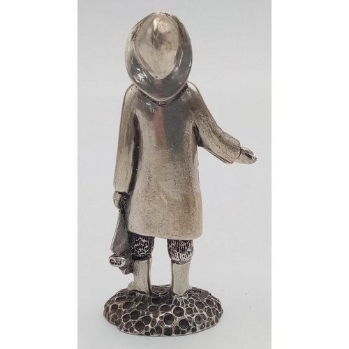 788 - A STERLING SILVER (TESTED AS) FIGURE OF A YOUNG BOY IN RAIN JACKET AND HAT WITH A BOAT POSSIBLY THE ... 