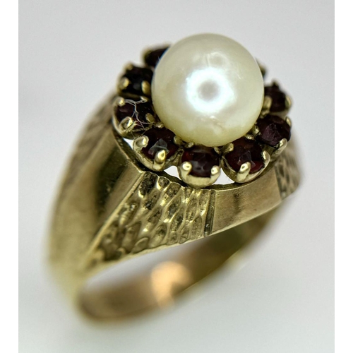 87 - AN UNUSUAL 8K GOLD RING WITH CENTRAL PEARL SURROUNDED BY GARNETS .. 3,2gms   size O