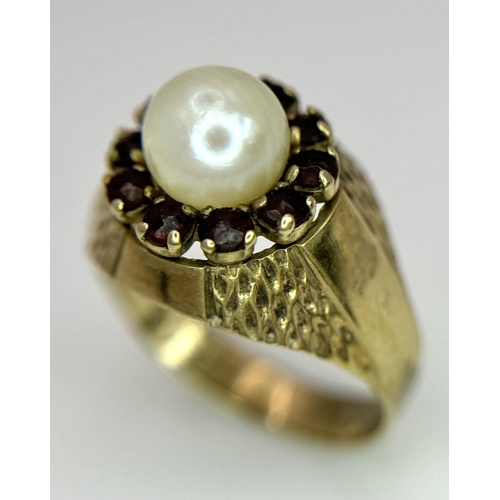 87 - AN UNUSUAL 8K GOLD RING WITH CENTRAL PEARL SURROUNDED BY GARNETS .. 3,2gms   size O